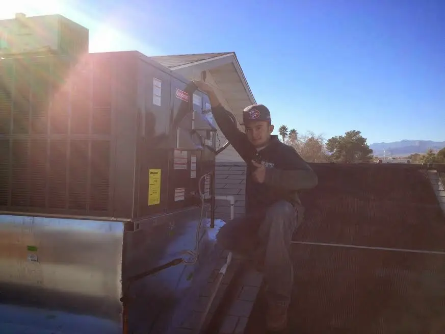 HVAC technician performing Heat Pump Repair on a rooftop unit in Raytown